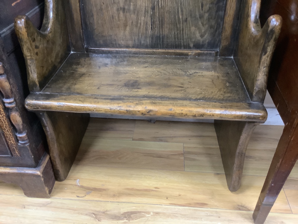 An 18th century style narrow oak panelled wing back settle